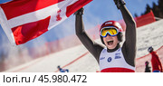 Skier celebrating victory with latvian flag at competition. Стоковое AI-изображение, AI-художник Юрий Поздников / Фотобанк Лори