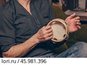 Man play tambourine, musician timbrel performs at concert in nightclub bar. Стоковое фото, фотограф Spirit River / Фотобанк Лори