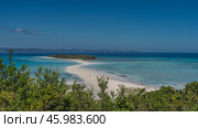 Beautiful tropical postcard landscape. A green island in the aquamarine ocean. Silhouettes of people on a winding sandbar. Boats near the shore. Green vegetation in the foreground. The blue sky. Стоковое фото, фотограф Вера Ивановна Кубарева / Фотобанк Лори