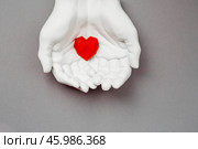 Stylish banner. In his hands, a red heart on a gray background is made of plaster. World Health, Love and Insurance Day. World Heart, Health and Organ Donor Day. Стоковое фото, фотограф Photojuli / Фотобанк Лори