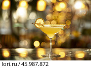 Sidecar cocktail garnished with lemon wheel and sugar rim on bar top in blurred restaurant setting. Стоковое AI-изображение, AI-художник Иван Рябоконь / Фотобанк Лори