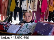 Блошиный рынок Самгори в Тбилиси, Грузия. Пожилая женщина, продавщица одежды. Редакционное фото, фотограф Evgenia Shevardina / Фотобанк Лори