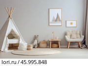 Cozy scandinavian interior design for children featuring teepee tent and armchair. Стоковое AI-изображение, AI-художник Иван Рябоконь / Фотобанк Лори