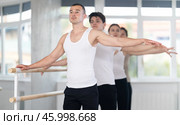 Sports young guy in black and white sportswear, participating 2nd position of ballet stance at barre with group in choreography studio. Стоковое фото, фотограф Яков Филимонов / Фотобанк Лори