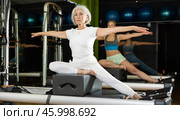 Gray-haired woman sitting on a Pilates platform. Стоковое фото, фотограф Яков Филимонов / Фотобанк Лори
