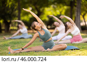 Girls practicing hatha yoga in summer garden, stretching in an asymmetrical seated asana Parivritta Janu Sirsasana with. Стоковое фото, фотограф Яков Филимонов / Фотобанк Лори