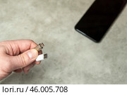 Смартфон на сером фоне и два кабеля USB-micro и USB Type-C в мужской руке на сером фоне. Кабель для заряда бытовой электроники. Редакционное фото, фотограф Sergei Gorin / Фотобанк Лори