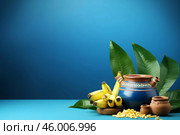 Clay pots, bananas and puffed rice creating a vibrant still life on blue. Стоковое AI-изображение, AI-художник Иван Рябоконь / Фотобанк Лори