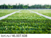 Artificial turf football field close up with white lines and blurred background. Стоковое AI-изображение, AI-художник Иван Рябоконь / Фотобанк Лори