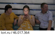 Gomel, Belarus - 25 July 2021: People on bench in an evening park. Pregnant young woman looks at her smartphone. Стоковое видео, видеограф Дмитрий Нечаев / Фотобанк Лори