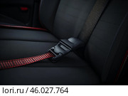 Red seat belt fastened on black car seat. Стоковое AI-изображение, AI-художник Иван Рябоконь / Фотобанк Лори