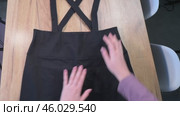 A woman is reviewing a sundress skirt. She is laying it out on the table. Photo from above. Стоковое видео, видеограф Vadzim Yakubovich / Фотобанк Лори