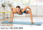 Young woman performing Parivrtta Utkata Konasana in yoga studio. Стоковое фото, фотограф Яков Филимонов / Фотобанк Лори