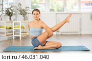 Girl performing seated twisting asana Matsyendrasana in yoga studio. Стоковое фото, фотограф Яков Филимонов / Фотобанк Лори