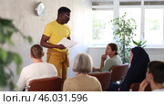 Portrait of confident african american tutor giving lecture to multiethnic group of adult students, standing in front of audience with papers in hands. Стоковое видео, видеограф Яков Филимонов / Фотобанк Лори