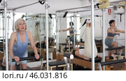 Mature woman doing lower back exercises while lying on Pilates bed in wellness center. Стоковое видео, видеограф Яков Филимонов / Фотобанк Лори