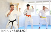 Confident martial arts instructor in white kimono with black belt leading judo kata training session for group of men of different ages. Стоковое видео, видеограф Яков Филимонов / Фотобанк Лори