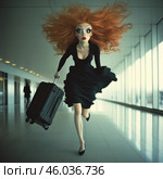 A girl with bright red loose hair running through a modern airport or gallery. Her hair flutters as she moves, adding dynamism and drama to the scene. The girl is wearing an elegant black dress and holds a small suitcase on wheels in her hand. She has expressive large eyes and unusual facial proportions, which makes the image stylized and comical. The light background with large windows emphasizes her energetic movement. The scene conveys a sense of haste, perhaps to catch a flight. Стоковое AI-изображение, AI-художник Анна Кривицкая / Фотобанк Лори