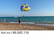 Парасейлинг для двух человек над морем с касанием воды на фоне пляжа. Редакционное видео, видеограф Владимир Шипикин / Фотобанк Лори