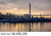 Russian navy warships are anchored in vladivostok harbor at sunset under the zolotoy rog bridge, creating a powerful image of maritime defense. Стоковое фото, фотограф Mikhail Davidovich / Фотобанк Лори