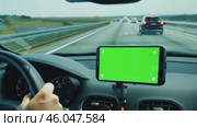 Navigator with green screen in the car dashboard. GPS module. Driver using smart phone with green background. Man steering wheel, driving on highway with smartphone navigation. Digital display monitor. Стоковое AI-видео, аниматор Марина Демидюк / Фотобанк Лори