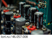 Electrolytic capacitors standing on circuit board in row. Стоковое AI-изображение, AI-художник Иван Рябоконь / Фотобанк Лори