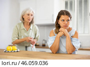 Senior woman scolding her adult daughter cooking breakfast in modern kitchen. Стоковое фото, фотограф Яков Филимонов / Фотобанк Лори