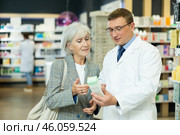 Middle-aged male pharmacist consulting old woman costumer about care product in box. Стоковое фото, фотограф Яков Филимонов / Фотобанк Лори