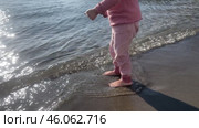 Cute baby girl playing with yellow sand and sea wave on beach shore pond. Стоковое видео, видеограф Spirit River / Фотобанк Лори