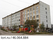 Детская площадка в городском дворе возле старого панельного дома. Обшарпанная стена дома. Проблемы благоустройства в городах. Город Магадан, Магаданская область, Дальний Восток России. Стоковое фото, фотограф Андрей Степанов / Фотобанк Лори