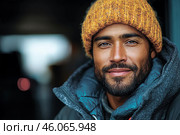 Man in cozy orange beanie and warm jacket smiles softly, standin. Стоковое AI-изображение, AI-художник Владимир Григорьев / Фотобанк Лори