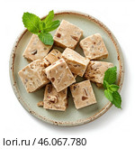 Delicious nougat cubes with mint leaves on a ceramic plate. Стоковое AI-изображение, AI-художник Иван Рябоконь / Фотобанк Лори