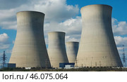 A nuclear power plant stands tall in the middle of a vast field, surrounded by greenery and under a clear sky. Стоковое AI-изображение, AI-художник Ирина Старикова / Фотобанк Лори