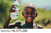 Smiling black child in African village with bottle of water. Water problems, global warming, drought, water shortage in the world, health problems, poverty and misery in countries. Climate change: from friendship to green grove. Стоковое AI-видео, аниматор ALLA YURTAYEVA / Фотобанк Лори