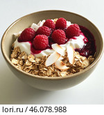 A healthy and delicious bowl of yogurt, oatmeal, raspberries, berry sauce and coconut chips. The base of the dish is thick white yogurt, on which fresh ripe raspberries are laid out and a little berry jam or sauce, giving the dish a rich color and flavor. Oatmeal adds texture, and toasted coconut chips decorate the dish, making it more flavorful. Serving in a ceramic bowl on a light background makes the image aesthetically pleasing. Стоковое AI-изображение, AI-художник Анна Кривицкая / Фотобанк Лори