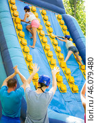 Young women competing in climbing with wood poles on inflatable slide. Стоковое фото, фотограф Яков Филимонов / Фотобанк Лори