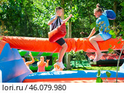 Cheerful teenager having fun with father on inflatable pillow fight arena. Стоковое фото, фотограф Яков Филимонов / Фотобанк Лори