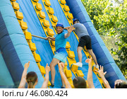Cheerful man climbing on inflatable slide with wooden poles. Стоковое фото, фотограф Яков Филимонов / Фотобанк Лори