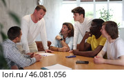 Interested adult man participating in volunteer work discussing project or event with group of ike-minded men of different ages and nationalities gathered around table. Стоковое видео, видеограф Яков Филимонов / Фотобанк Лори