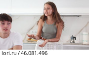 Upset young man sitting at the kitchen-table with his back to his wife disputing with him. Стоковое видео, видеограф Яков Филимонов / Фотобанк Лори