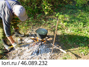 Мужчина подкладывает дрова в костер над которым варится уха. Стоковое фото, фотограф Роман Лукьянов / Фотобанк Лори