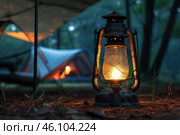 Illuminated lantern casting warm glow on campsite. Стоковое AI-изображение, AI-художник Иван Рябоконь / Фотобанк Лори