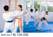 Teen girl honing grappling techniques during kumite with boy at karate training. Стоковое фото, фотограф Яков Филимонов / Фотобанк Лори