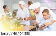 While children cooking class, male chef help small girl thoroughly stir homogeneous dough with whisk. Стоковое фото, фотограф Яков Филимонов / Фотобанк Лори