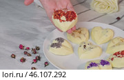 Manual presented chocolate sweets with drier strawberries and nuts, with flowers on a plate. Стоковое видео, видеограф Zakharova Natasha / Фотобанк Лори