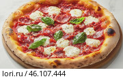 Top view footage of italian pizza with tomato sauce, dry and spicy salsiccia, mozzarella, basil leaves, olive oil, appetizing. Italian cuisine and gastronomic tour concept. Culinary video blog. Стоковое AI-видео, аниматор Ирина Михайличенко / Фотобанк Лори