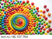 Colorful dragee candies in the assortment on a white background. Various sweets, confectionery and dragees of different shapes and colors. Bright rainbow hues. Стоковое AI-изображение, AI-художник Photojuli / Фотобанк Лори