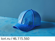 Blue waterproof cap resisting water drops on blue background. Стоковое AI-изображение, AI-художник Иван Рябоконь / Фотобанк Лори