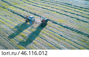Haymaking. A lone farmer on a tractor with a trailed round baler working on a field with swaths of cut grass. Drone footage. Стоковое фото, фотограф Роман Дзюбало / Фотобанк Лори