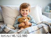 A cute boy hugs a teddy bear, sitting in a cozy bed, a small child hugs a toy and gets ready for bed. A healthy night's sleep. Стоковое AI-изображение, AI-художник Photojuli / Фотобанк Лори